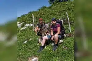 Zwei Wanderinnen und ihre Hunde machen eine Pause am Wegrand